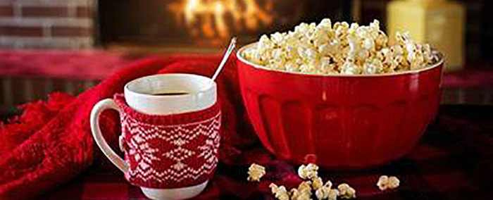 red and white mug next to a bowl of popcorn infront of a brick fireplace