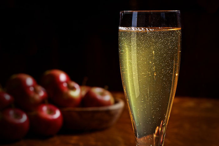 cider in a glass with apples in the background