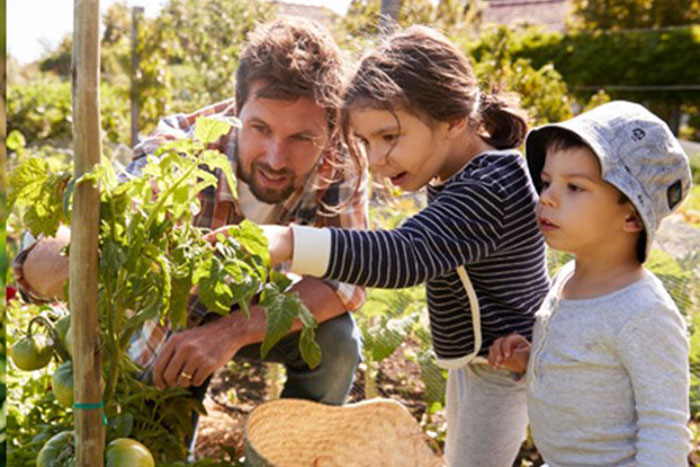 two children with an adult in a garden