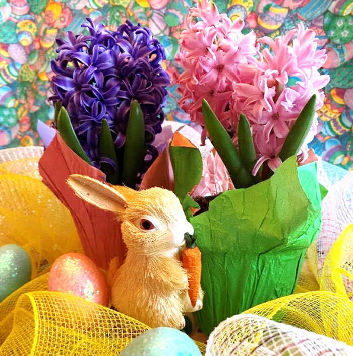 arrangement of purple flowers next to arrangement of pink flowers with bunny statue in front