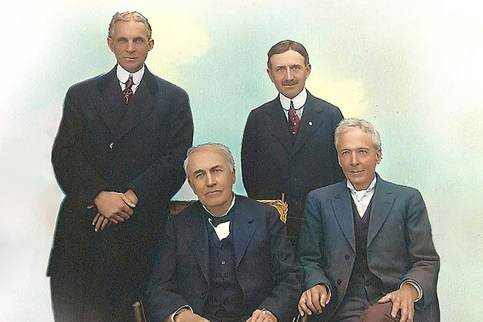 two men sitting with two men standing behind all in suits