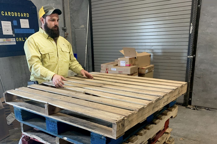 person standing next to stack of pallets