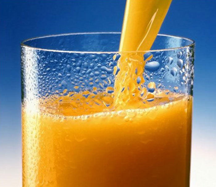orange juice getting poured into a glass