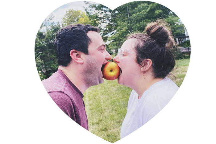 man and woman bitting on the same apple face to face