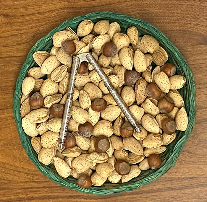 bowl of tan shelled nuts with hand nut cracker