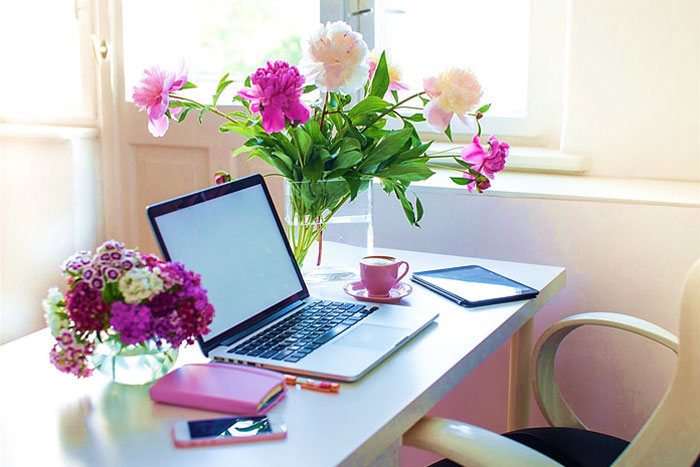 computer desk with multiple bouqets of multi-colored flowers